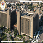 Aerial view of a downtown area with three tall beige office buildings surrounded by roads and trees   جامعة الرافدين   مدير الموقع عمار محمود ابو الشعير   جامعة الرافدين   مدير الموقع عمار محمود ابو الشعير