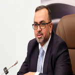 Man in a dark suit and glasses speaks into a microphone at a formal meeting   جامعة الرافدين   مدير الموقع عمار محمود ابو الشعير   جامعة الرافدين   مدير الموقع عمار محمود ابو الشعير