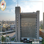 Tall rectangular office building with a grid of windows in a cityscape under a clear blue sky   جامعة الرافدين   مدير الموقع عمار محمود ابو الشعير   جامعة الرافدين   مدير الموقع عمار محمود ابو الشعير