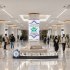 A spacious university lobby with a central pillar display reading 'Al Rafidain University' and students walking or sitting nearby.